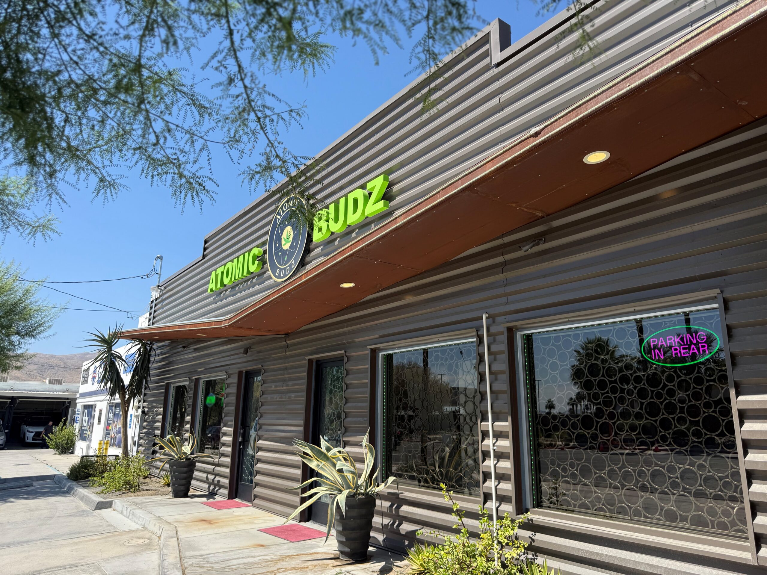 Atomic Budz dispensary storefront under blue sky