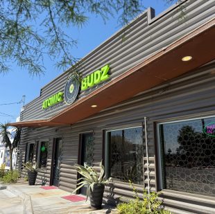 Atomic Budz dispensary storefront under blue sky